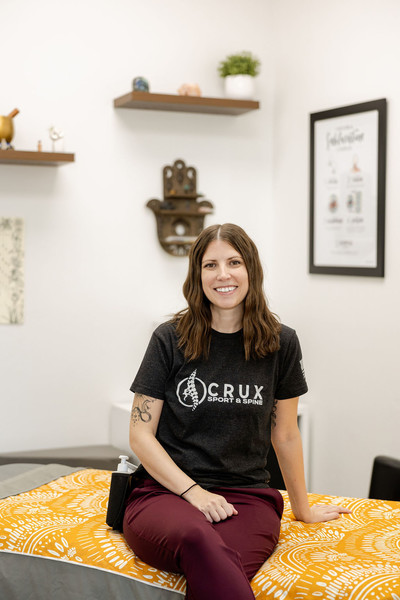 Massage therapist sitting on a massage table smiling and waiting for her patient at a chiropractic clinic in St. George, UT