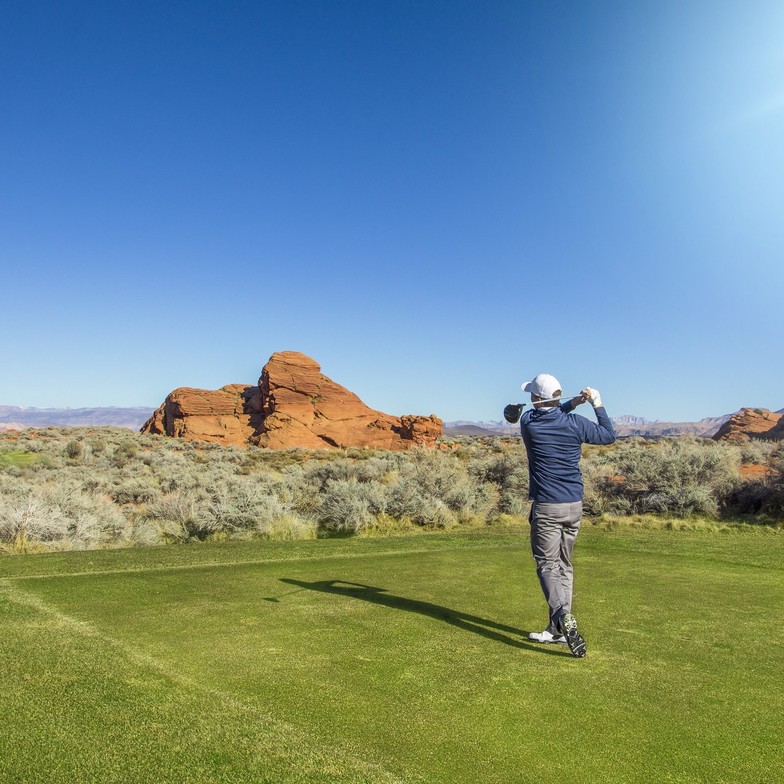 Golfer swinging on a scenic course in St. George, Utah, representing golf with low back pain.