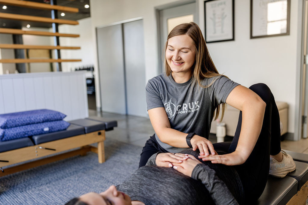 Chiropractor working with a patient on abdominal muscle engagement during a therapy session at Crux Sport & Spine in St. George, Utah.